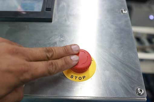 Hand activating emergency stop button.