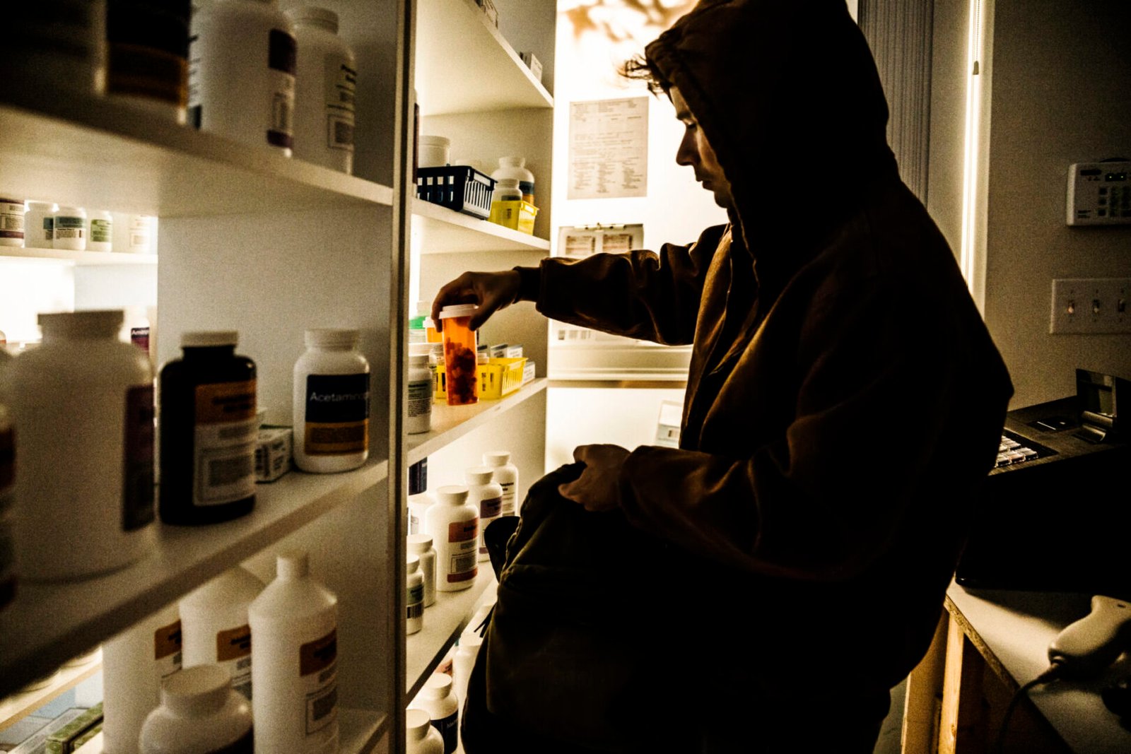 Person taking medicine from pharmacy shelf